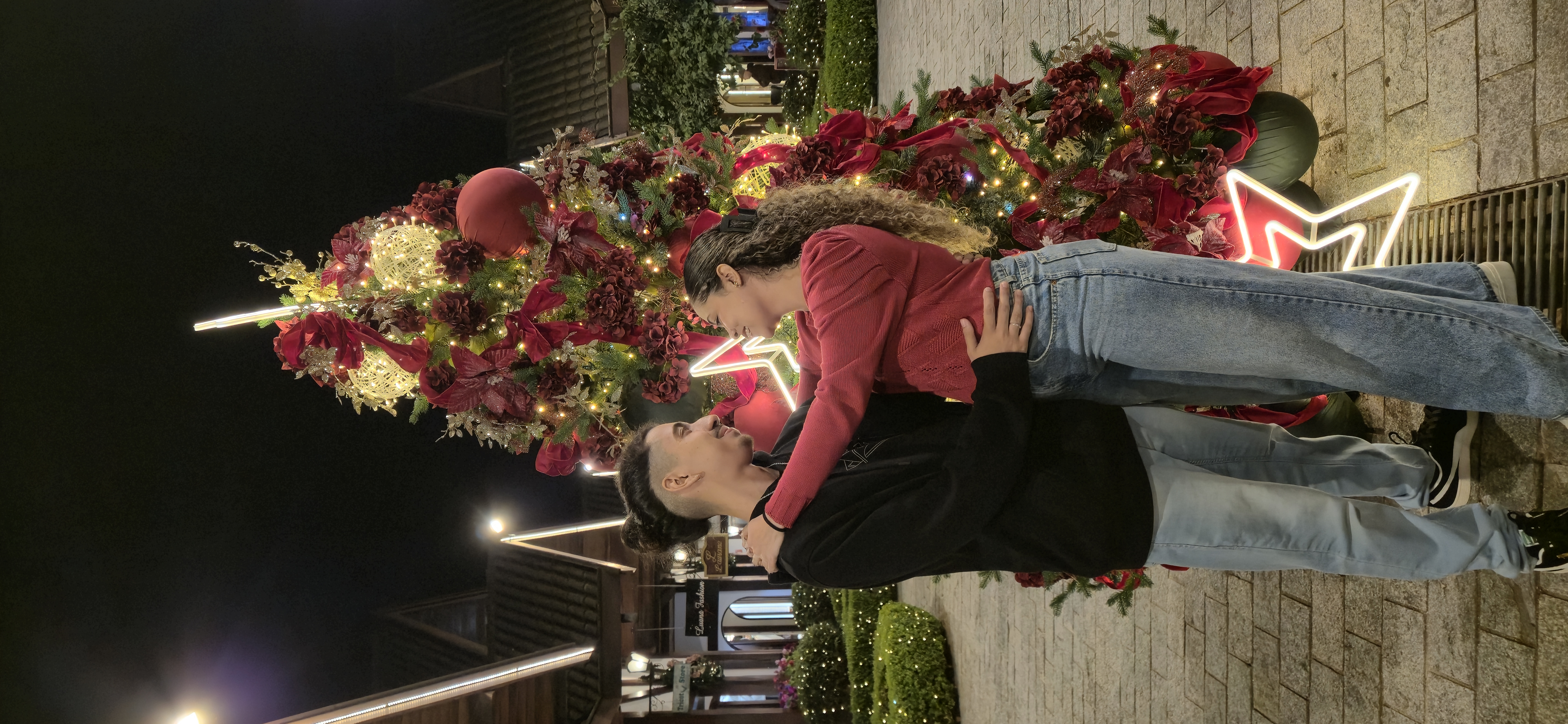 Raíla e Ramon abraçados em frente à árvore de Natal